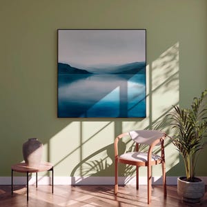 Peut inclure: Int&eacute;rieur serein avec une grande &oelig;uvre d'art encadr&eacute;e repr&eacute;sentant un paysage bleu et blanc. Une chaise moderne, une petite table d'appoint avec un vase et une plante en pot sont &eacute;galement pr&eacute;sents. La pi&egrave;ce est peinte dans une teinte verte douce.