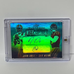 May include: A collectible sports card encased in a clear protective holder. The card features two football players, the text "LEAF ELECTRUM INTERMETALLIC", and player signatures. The card has a holographic, iridescent finish.