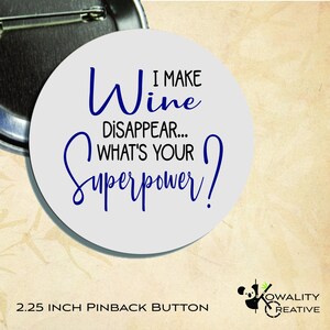 May include: A round pinback button with the text "Wine I make disappear... What's your superpower?" in blue script on a light gray background. The button is 2.25 inches in diameter.