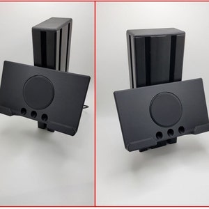 May include: A black plastic stand with a slot for a tablet or phone. The stand has a circular cutout in the center and a small lip on the front to hold the device in place.