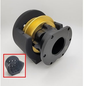 May include: A black and gold steering wheel adapter with a black plastic housing. The adapter has a black plastic ring with a series of holes around the circumference. The adapter is designed to fit a steering wheel with a 6-bolt pattern.