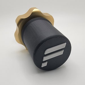May include: A black bottle with a gold top and a white "F" logo. The bottle has a textured surface.