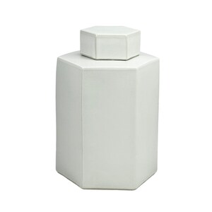 Peut inclure: Pot en céramique hexagonale blanche avec un couvercle. Le pot a une finition lisse et mate.