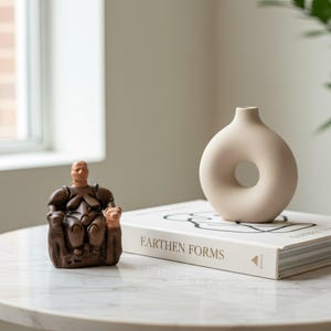 Cybele Goddess figurine displayed on a rustic wooden desk beside pottery and dried flowers. The natural setting evokes the atmosphere of an ancient shrine, symbolizing fertility and harmony. A perfect handmade art piece for boho or archaeology-inspired home decor.