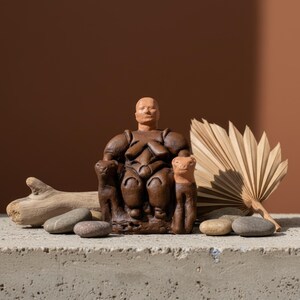 The Neolithic Mother Goddess statue placed near books and candles in a sunlit boho interior. The warm terracotta tones and spiritual presence of the piece bring ancient Anatolian serenity into modern living spaces. A timeless expression of the divine feminine by ArkeoArt.
