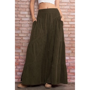 May include: A long, dark green corduroy skirt with a tiered design and pockets. The skirt has a high waist and a flowy silhouette.