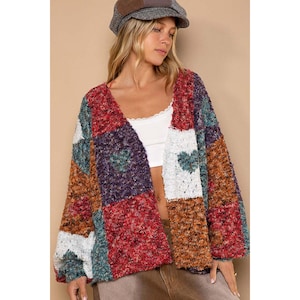 May include: A multi-colored patchwork cardigan with a fuzzy texture. The cardigan has a V-neck and long sleeves.
