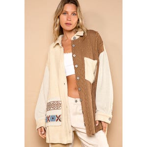 May include: A long-sleeved, button-up shirt with a patchwork design. The shirt is made of a soft, corduroy fabric and features a brown and cream color scheme. The shirt has a large pocket on the left side with embroidered details.