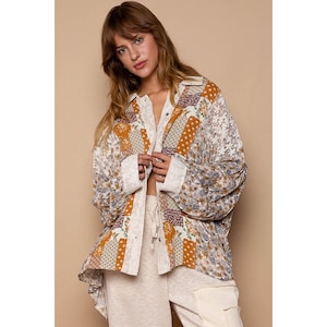 May include: A long-sleeved, patchwork shirt with a floral print in shades of brown, white, and blue. The shirt has a relaxed fit and a button-up front.
