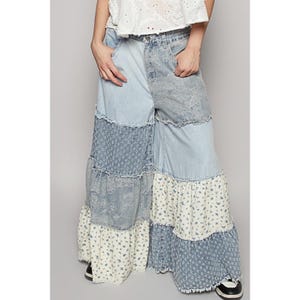 May include: Wide-leg denim pants with a patchwork design featuring different shades of blue denim and floral fabric. The pants have a tiered, ruffled hemline.