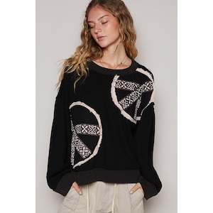 May include: Black waffle knit sweater with two embroidered peace signs. The sweater has a relaxed fit and a cropped length.