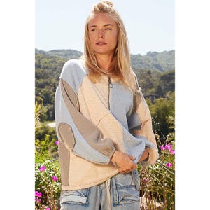May include: A light blue, beige, and brown patchwork pullover sweater with a zipper closure. The sweater has a relaxed fit and long sleeves.