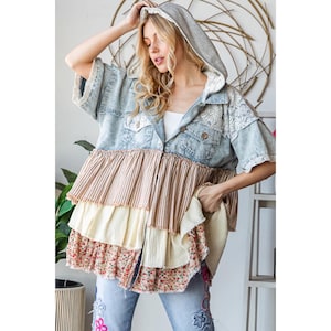 May include: A light blue denim jacket with a hooded overlay and a layered ruffle trim in shades of brown, cream, and pink floral print.