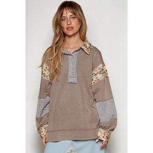 Puede incluir: Una camisa marrón de manga larga con cuello y cierre de botones. La camisa tiene detalles de patchwork en las mangas y el cuello, con estampados florales y a cuadros.