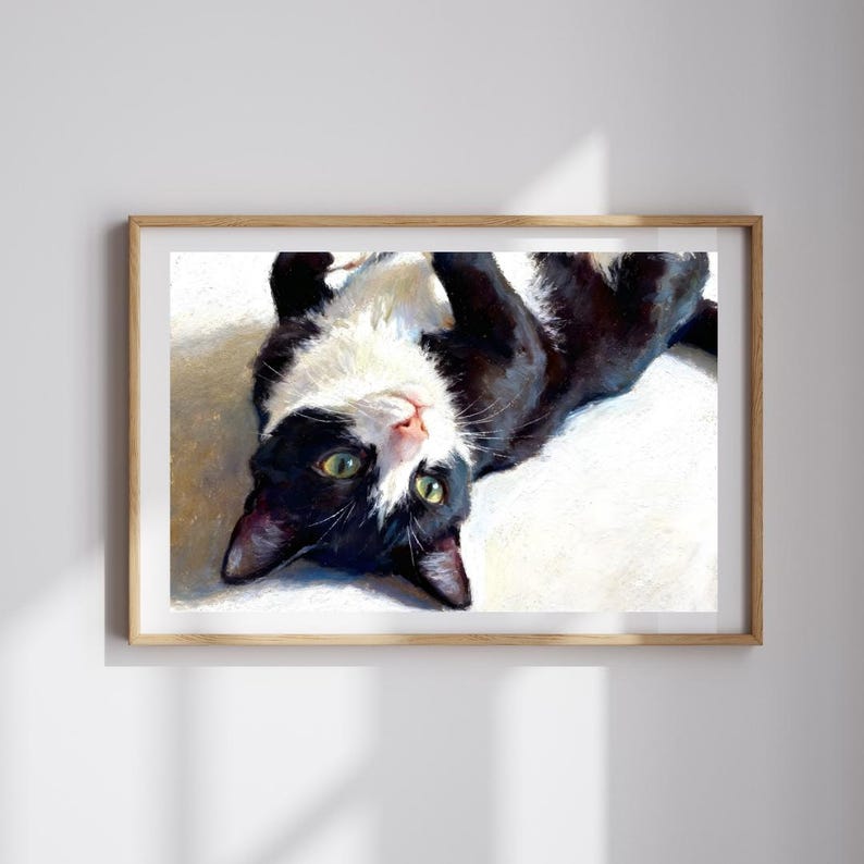 K&ouml;nnte beinhalten: Ein gerahmtes &Ouml;lgem&auml;lde einer schwarz-wei&szlig;en Katze, die auf dem R&uuml;cken liegt. Die Katze hat gr&uuml;ne Augen und schaut nach oben. Das Gem&auml;lde zeichnet sich durch sichtbare Pinselstriche und eine kontrastreiche Farbpalette aus.