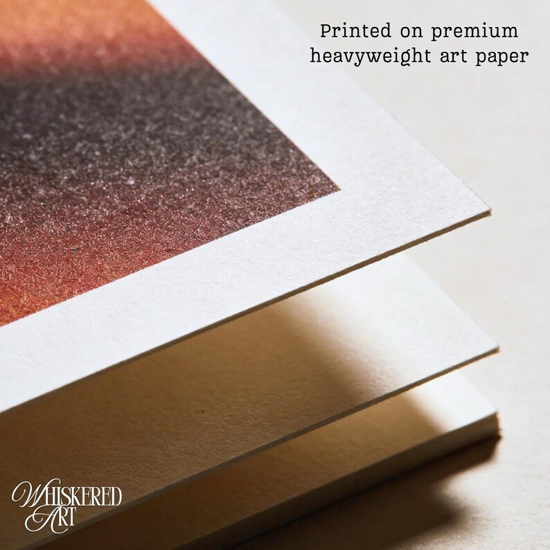 K&ouml;nnte beinhalten: Ein Stapel aus drei Bl&auml;ttern dickem, wei&szlig;em Papier, wobei das oberste Blatt einen Farbverlauf in Braun- und Oranget&ouml;nen aufweist. Der Text 'Printed on premium heavyweight art paper' ist sichtbar, zusammen mit dem Logo 'Whiskered Art'.