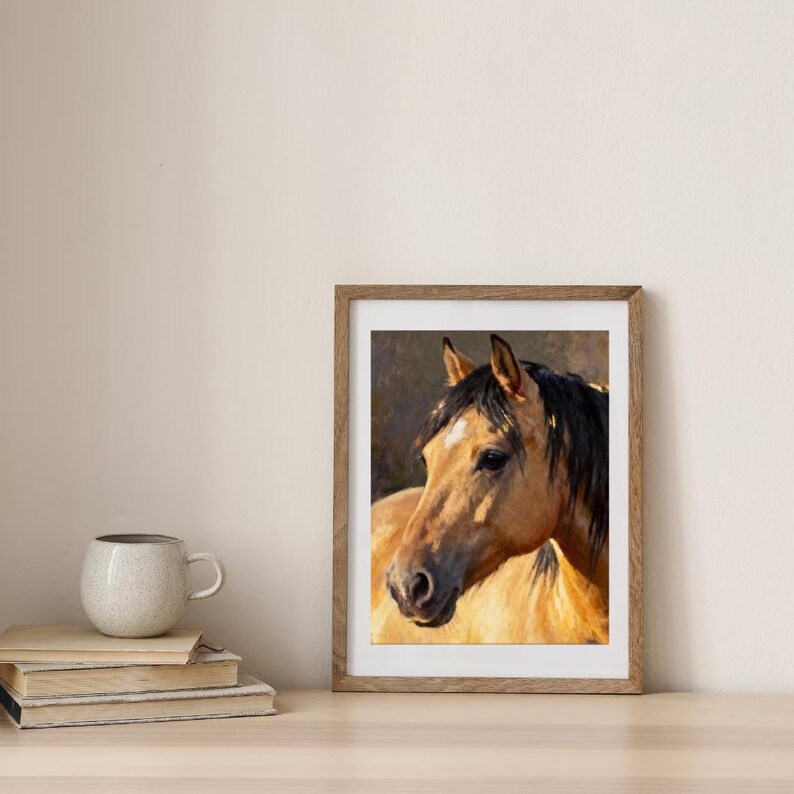 May include: A framed oil painting of a buckskin horse with a black mane and a white star on its forehead. The horse is depicted in profile, facing left, with warm golden-brown tones and soft lighting against a dark, muted background.