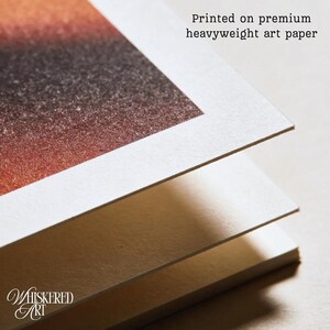 May include: A stack of three thick sheets of white art paper with a textured surface. The top sheet features a printed gradient of orange, brown, and black colors. The text "Printed on premium heavyweight art paper" is visible at the top.