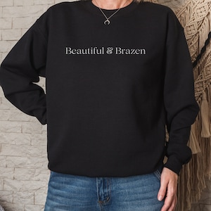 May include: Black sweatshirt with the text "Beautiful & Brazen" in white lettering.