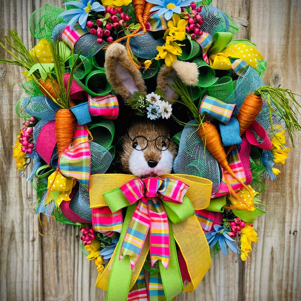 Easter /Spring wreath featuring a large rabbit head sporting a top hat and glasses, surrounded by lg carrots, colorful flowers and ribbons