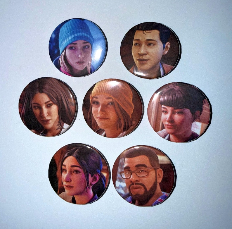 May include: A collection of seven round pinback buttons featuring portraits of various people. The buttons display images of individuals with diverse hairstyles and expressions, set against a dark background. The buttons are arranged on a white surface.