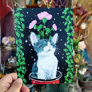 May include: A black and white cat with pink flowers growing out of its head, sitting in a red pot with green vines. The background is black with white stars.