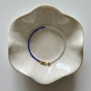 May include: A blue and light blue beaded bracelet with a gold clasp.