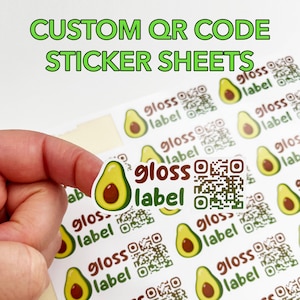 May include: Custom QR code sticker sheets featuring avocado and gloss label designs. The stickers are white with a green avocado graphic and brown text. The text "CUSTOM QR CODE STICKER SHEETS" is at the top.