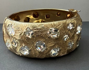 Rare vintage 1960s CASTLECLIFF signed bangle/bracelet/cuff featuring clear rhinestones set into textured gold-tone metal.  Hinge and lock.