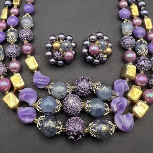 Vintage 1950s necklace and clip earrings set. Beads in shades of purple, gold tone. Silver-tone accents. Japan marked.
