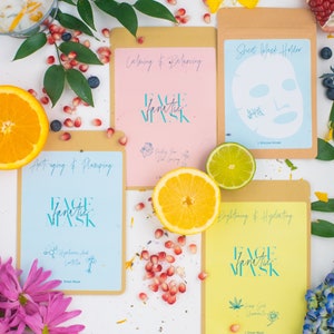 May include: Four different face mask packaging designs with various colours and text. The packaging is made of brown paper with a clear window to show the mask inside. The text on the packaging includes the words "Face Fanatic Mask", "Calming & Balancing", "Sheet Mask Holder", "Anti-aging & Plumping", "Brightening & Hydrating", "Hyaluronic Acid", "Hemp Seed", "Chamomile", "Pink Clay", "Red Clay", "Silicone Holder", "Sheet Mask".