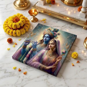 Op de afbeelding: Een canvas print met een afbeelding van de hindoeïstische goden Krishna en Radha, in levendige kleuren. Het kunstwerk toont het paar met Krishna die fluit speelt. De scène is omgeven door goudsbloemen en een brandende kaars.