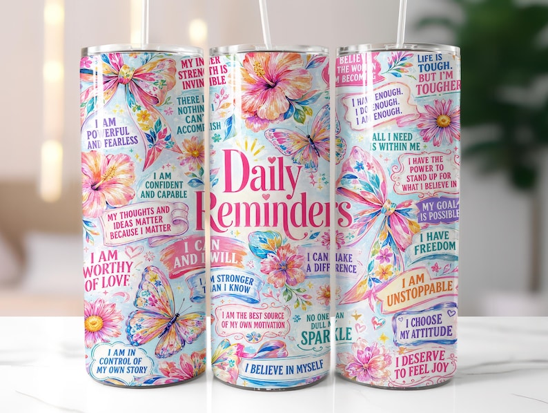 May include: A set of three 20 oz. stainless steel tumblers with a floral and butterfly design. Each tumbler features inspirational quotes and the words "Daily Reminders" in pink. The tumblers have a light blue background.