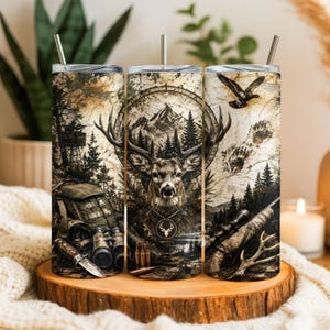 Puede incluir: Un vaso cilíndrico con un tema de caza detallado que presenta una cabeza de ciervo central, paisaje de montaña, pinos, un puesto de caza, mochila, binoculares, cuchillo, municiones, un rifle y un pato volando en tonos marrones y beige.
