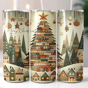 Op de afbeelding: Drie roestvrijstalen bekers met een kerstthema. Het ontwerp toont een kerstboom, huizen en ornamenten, met de tekst "Merry Christmas". Elke beker heeft een wit rietje. Geschikt voor koude dranken.