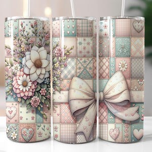 May include: Three stainless steel tumblers with a patchwork quilt design. The tumblers feature a floral design with pink, white, and green flowers. The center tumbler has a large white bow with pink accents.