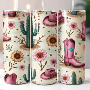 May include: A tumbler with a repeating pattern of pink cowboy boots, hats, cacti, sunflowers, and pink flowers on a cream background. The tumbler has a white straw and is designed with a country western theme.