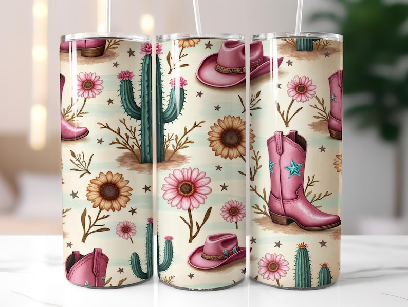 May include: A tumbler with a repeating pattern of pink cowboy boots, hats, cacti, sunflowers, and pink flowers on a cream background. The tumbler has a white straw and is designed with a country western theme.