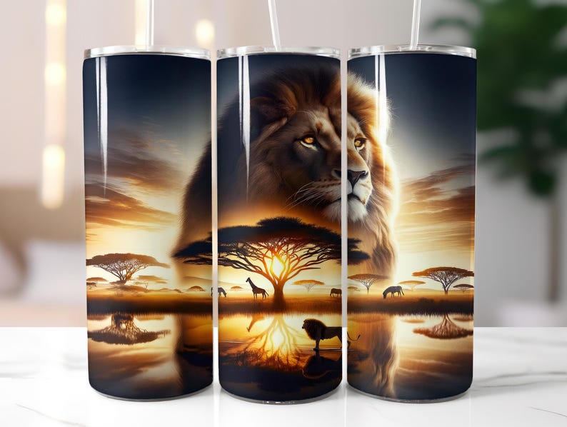 May include: A set of three stainless steel tumblers featuring a majestic lion against a sunset backdrop. The design includes African savanna trees, wildlife silhouettes, and a reflective water surface, creating a vibrant and detailed scene.