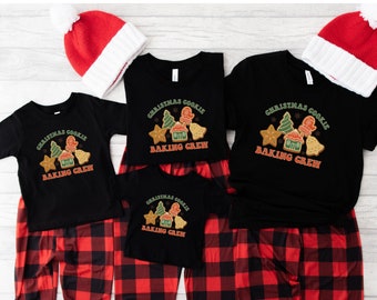 May include: A set of three black t-shirts with red and green Christmas cookie designs and the text "Christmas Cookie Baking Crew". The shirts are paired with red and black plaid pajama pants.