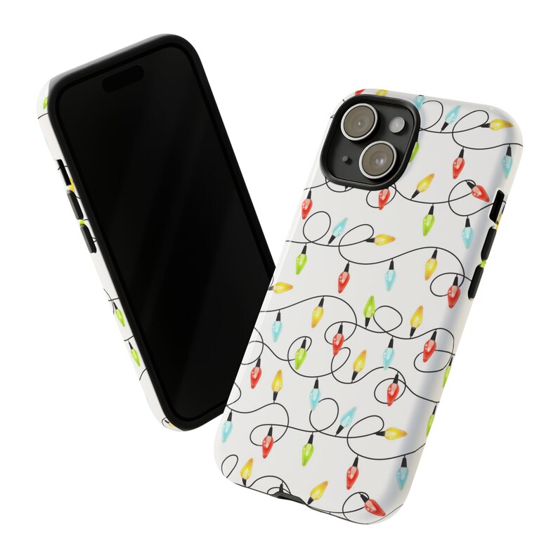 Puede incluir: Una funda de tel&eacute;fono blanca con un borde negro y un patr&oacute;n de luces navide&ntilde;as de colores. La funda tiene un recorte para el objetivo de la c&aacute;mara.