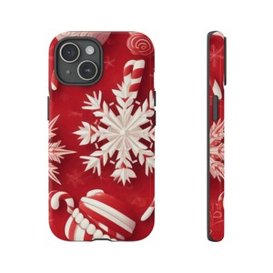 Puede incluir: Una funda de tel&eacute;fono roja con un dise&ntilde;o de copo de nieve blanco y bast&oacute;n de caramelo.