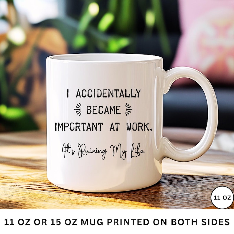 Op de afbeelding: Witte keramische mok met een gebogen handvat. De mok heeft de tekst "I ACCIDENTALLY BECAME IMPORTANT AT WORK. It's Ruining My Life." in zwarte letters. De mok is 312 ml en aan beide zijden bedrukt.