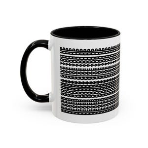 May include: White ceramic coffee mug with a black interior, handle, and a repeating black pattern of various shapes. The pattern includes arrows, circles, and other geometric designs. The mug is designed for hot beverages.