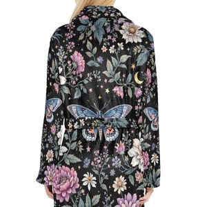 May include: Black floral robe with a butterfly and moon design. The robe features a dark background with pink, purple, and white flowers, green leaves, and a light blue butterfly. The robe has a belt and long sleeves.
