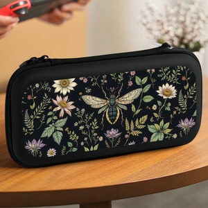 May include: Black floral print Nintendo Switch case with a bee design. The case has a zipper closure and a soft interior lining.