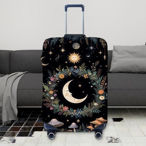 Peut inclure: Housse de valise noire avec un motif de couronne florale représentant une lune croissante, le soleil et des étoiles. La couronne est entourée de champignons et de verdure.