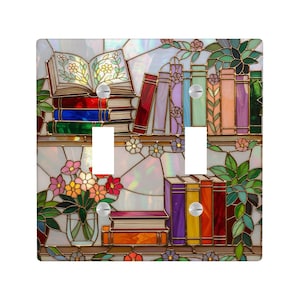 Puede incluir: Cubierta decorativa para interruptor de luz con diseño de estantería de vidrieras. El diseño incluye pilas de libros de varios colores, flores y un libro abierto. La cubierta tiene dos juegos de aberturas para interruptores de luz y está sobre un fondo blanco.