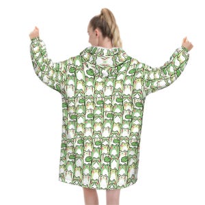 May include: A white hooded sweatshirt with a repeating pattern of green cartoon frogs. The frogs have white bellies and are holding green lily pads. The sweatshirt has long sleeves and a hood.