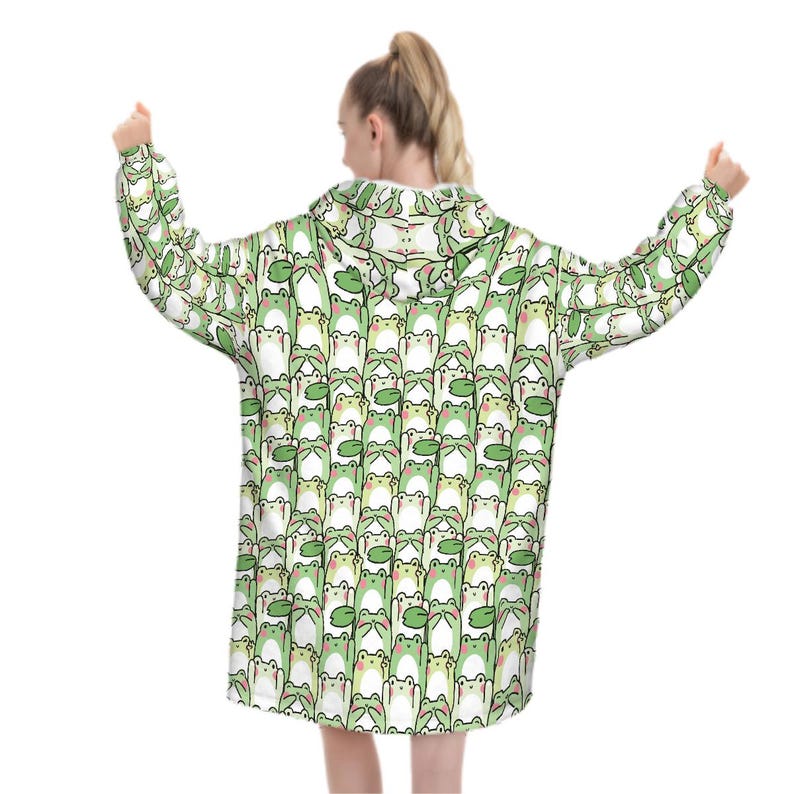 May include: A white hooded sweatshirt with a repeating pattern of green cartoon frogs. The frogs have white bellies and are holding green lily pads. The sweatshirt has long sleeves and a hood.